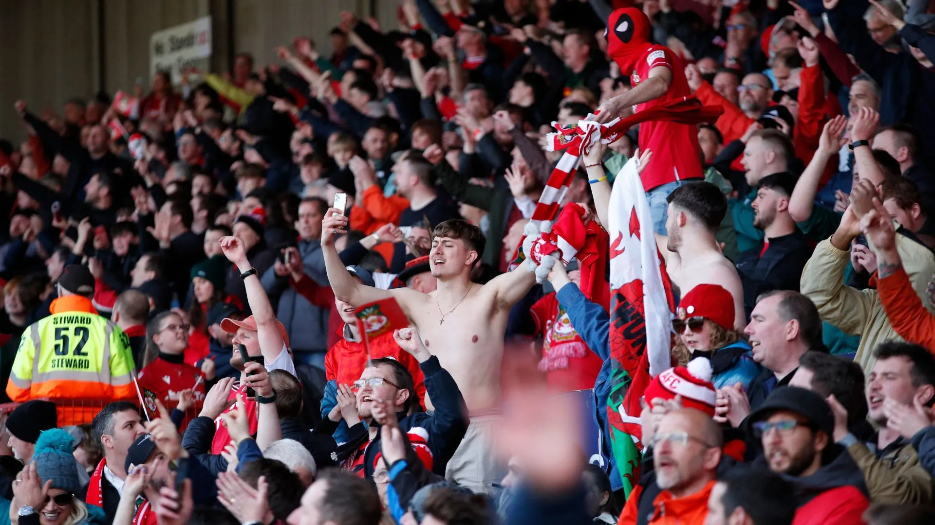 Các cổ động viên Wrexham ăn mừng cuồng nhiệt trên khán đài sân nhà